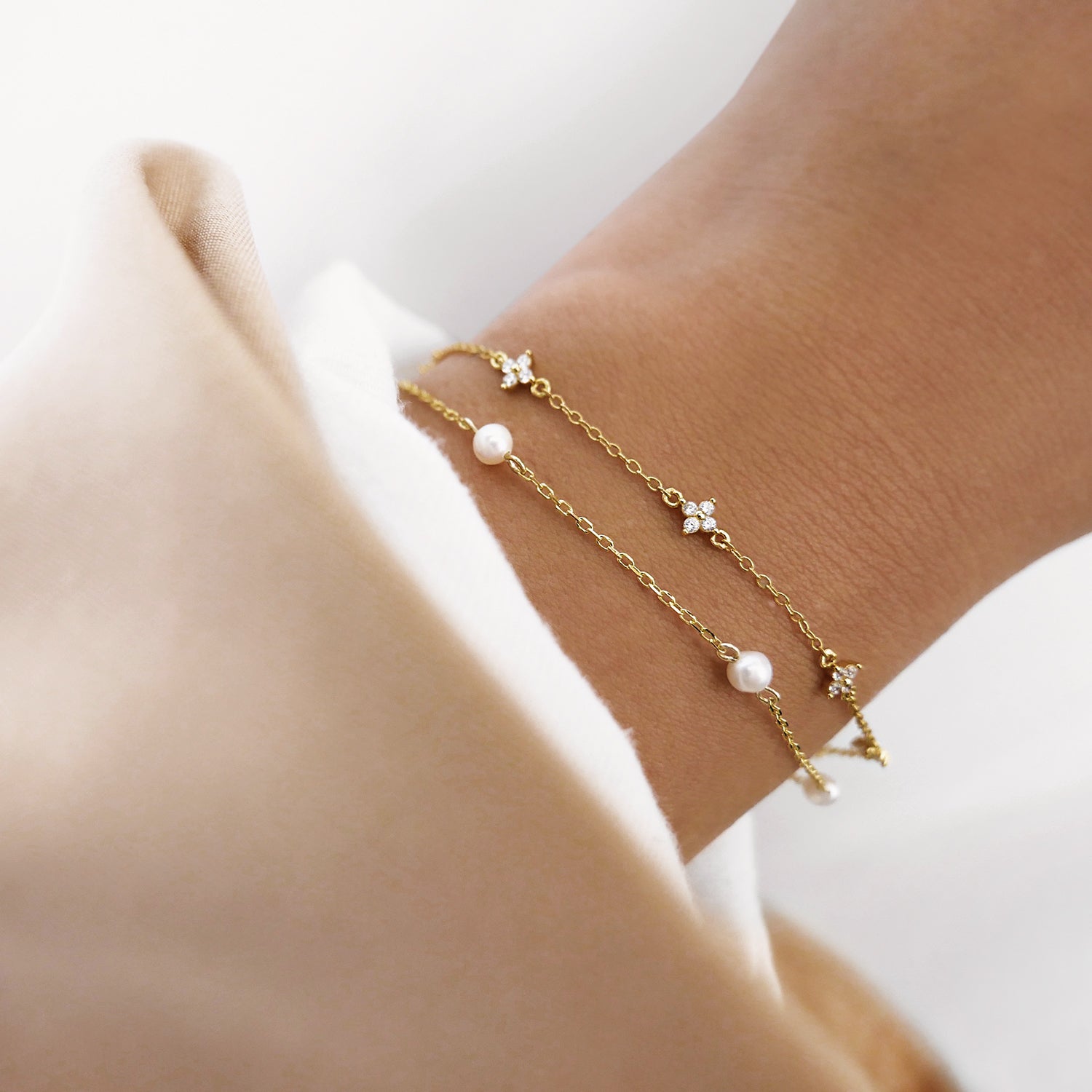 Iris gold bracelet with white zirconia clovers styled with pearl chain