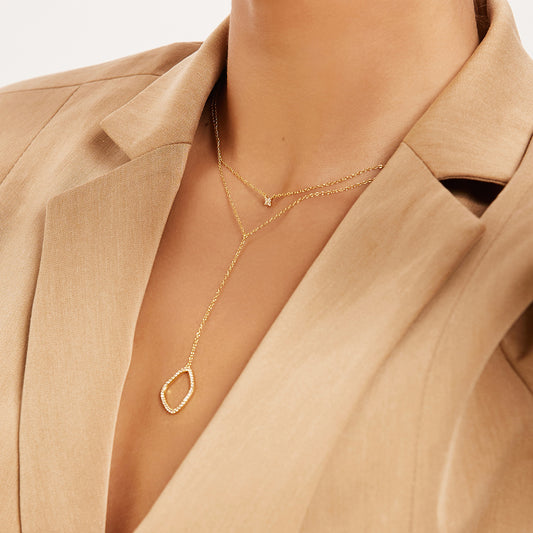 Paola gold drop necklace with sculptural white zirconia stone pendant styled with clover pendant necklace